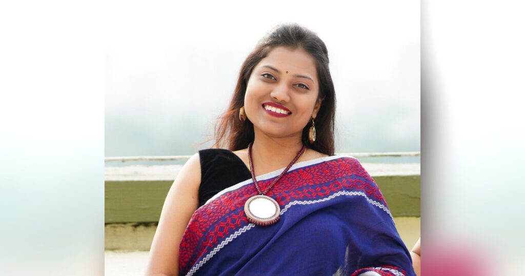 Woman wearing a navy blue handloom cotton saree with a red and white woven border, styled for the workday